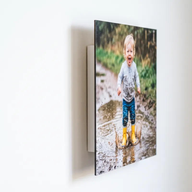 A Floto photo tile seen from the side, standing clear of a white wall on its hidden floating back