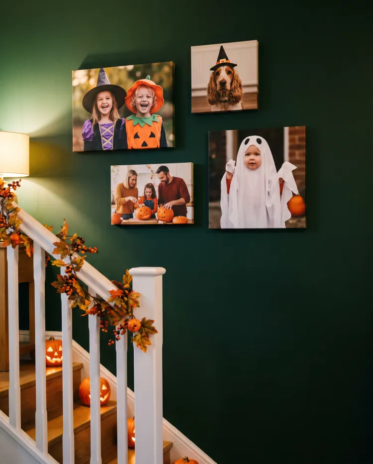 Canvas prints on a green hallway wall at Halloween: children in witch and pumpkin costumes, a spaniel in a witch hat and a family carving pumpkins