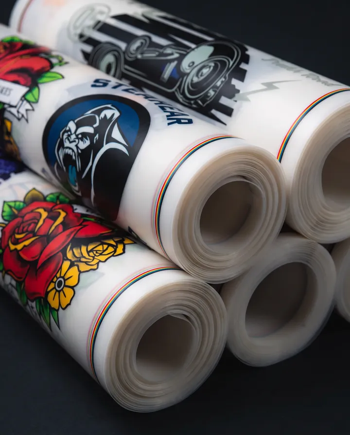 Rolls of DTF transfer film printed edge to edge with full-colour designs, a gorilla, a red rose and a car