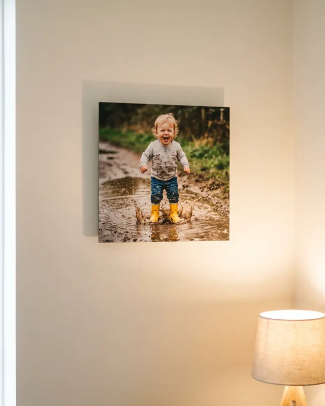 A single Floto photo tile of a toddler splashing in a puddle on a living room wall